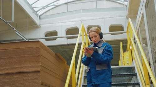 A Female Worker at a Recycled Paper Packaging Factory Controls Quality of Corrugated Cardboard