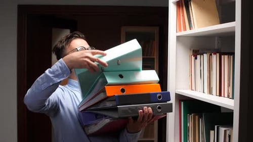 Office Worker Carrying a Pile of Ring Binders in the Archive