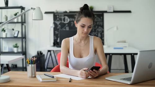 Woman writes and uses phone with green screen