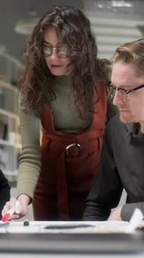 Colleagues And Clients Talking Strategy With Project Blueprint In Creative Office Productive