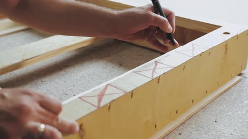 Closeup of Man Hand Notices the Length of the Wooden Square and Draws a Short Straight Lines Slow