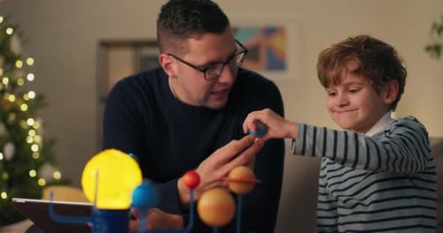 Dad and Son Assemble Solar System Model at Home