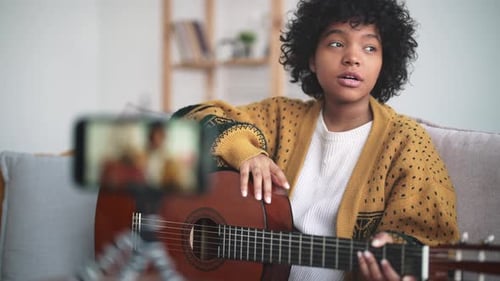 Young Woman Teaching Guitar Online at Home