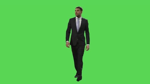 Businessman in a suit is walking on a mock-up green screen in the background.