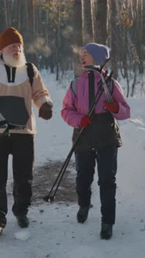 Senior Couple Walking with Skis in Winter Forest