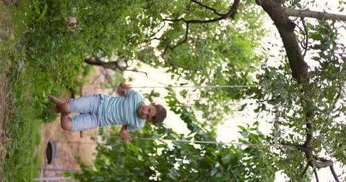 Happy Little Boy Swinging on a Swing in the Garden