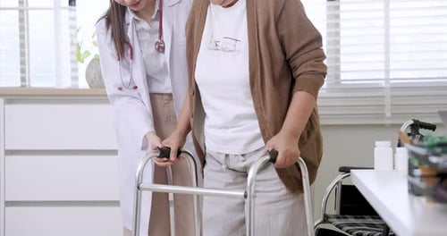 Young Doctor Assists Senior Woman with Walker Indoors