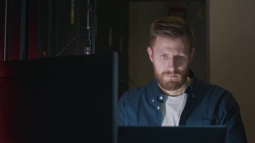 Man Working on Computer in Dark Server Room