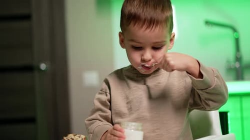 Happy Boy Eats Yogurt in High Chair Indoors