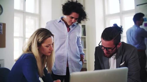 Young business team collaborating on a laptop in a modern open office space