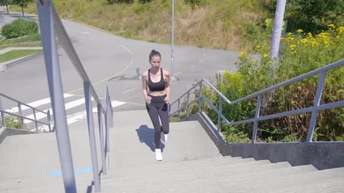 Woman Runs Up Concrete Steps Outdoors on Sunny Day