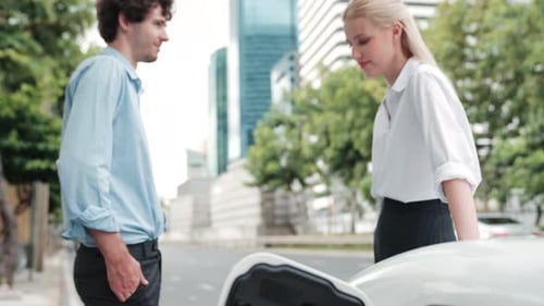 Progressive Businessman and Businesswoman Use Charging Station for EV Car