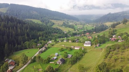Flight Over a Small Village Located Among the Green Mountains
