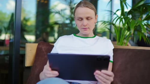 Young Woman Using Tablet in Modern Cafe