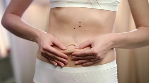 Gros plan de l'abdomen sain de la jeune femme après un entraînement physique au gymnase