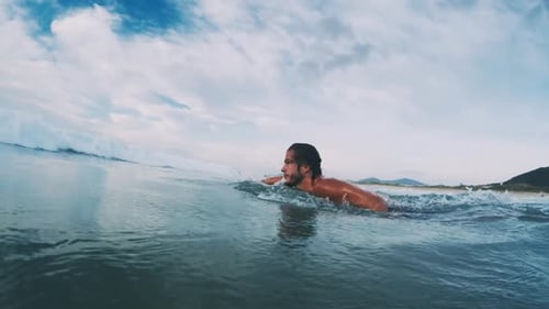 Bodysurfer with handplane. Young man dives under the ocean wave with handboard