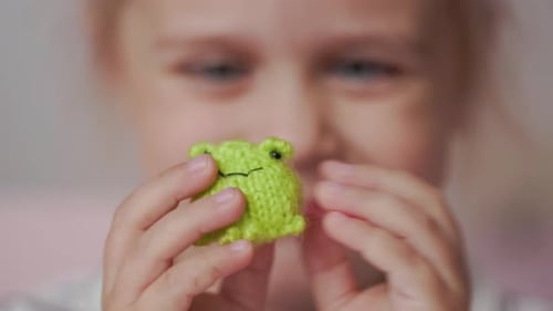 Mädchen spielt mit kleinen gestrickten Tierspielzeugen in einem Zimmer zu Hause