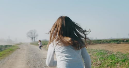 Two Children Running Down Dirt Road in Countryside