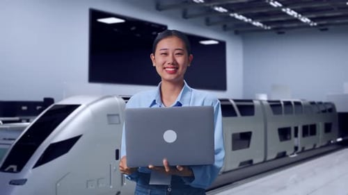 Woman Holding Laptop in Front of Modern Train