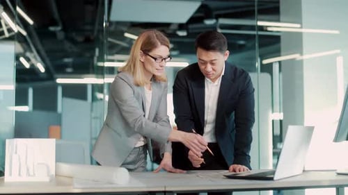 Architects Collaborating on Blueprint in Modern Office