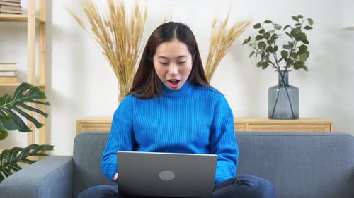 Woman Celebrates Success While Using Laptop at Home