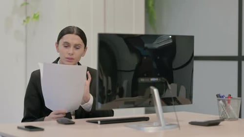 Woman Reviews Documents and Types at Office Desk