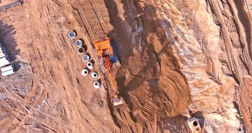Excavator at Busy Construction Site Aerial