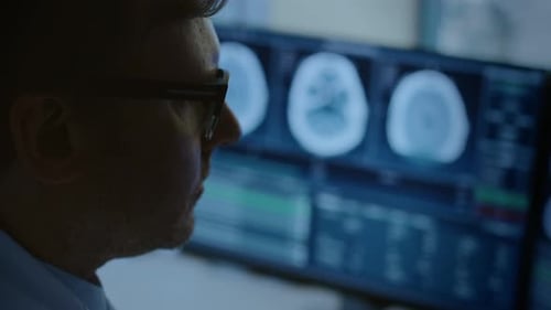 Close-up Portrait of Professional Doctor Looking at MRI or CT Scan Images on His Computer Monitor,