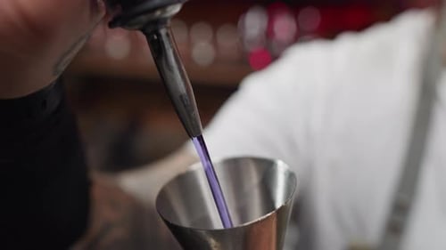 Cámara lenta del camarero vertiendo alcohol de una botella en una jarra en un bar