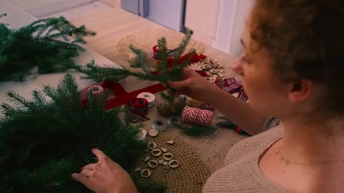Woman Making Christmas Wreath with Evergreen Branches