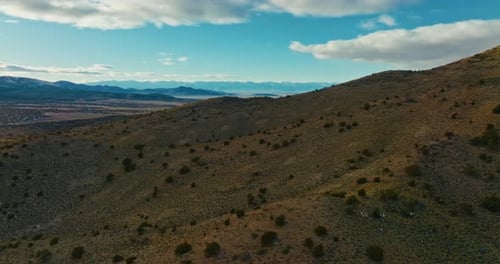 Drone shot of Nevada high desert at sunset. Camera slowly flies toward mountains and pans left