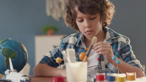 Boy Paints Solar System Model at Home