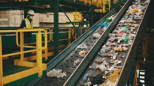 Recycling Plant Worker Overseeing Waste Conveyor Belt