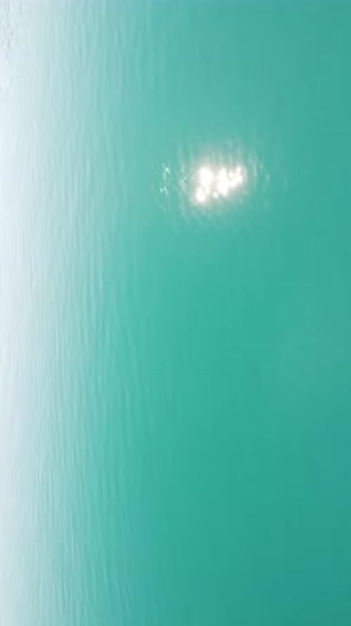 Vertical Aerial View on Sea Water Surface Camera Flies Over Clear Sea Water Sun Glare Abstract
