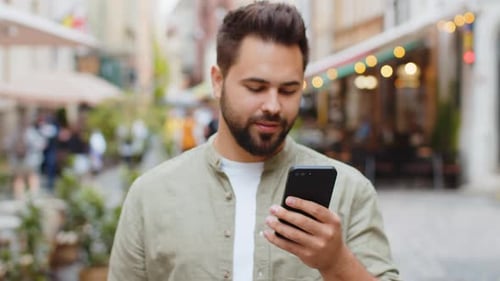 Man Smiling with Phone on Urban Street
