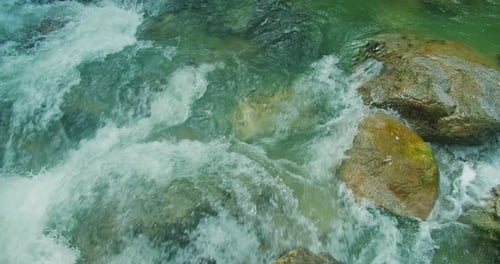 Powerful stream of blue water moves very fast over rocks
