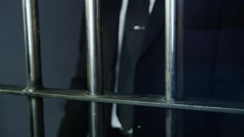 White collar crime - hands on prison bars in suit and tie HD