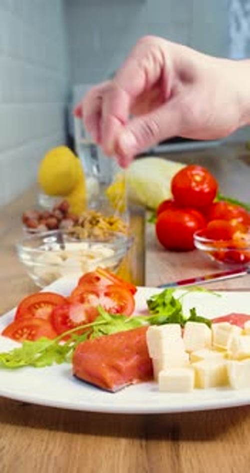Closeup Vertical Video of a Male Hand Sprinkles Fish and Cheese with Salt