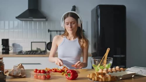 Cooking Woman Listening Music in Earphones Chopping Vegetables in Kitchen