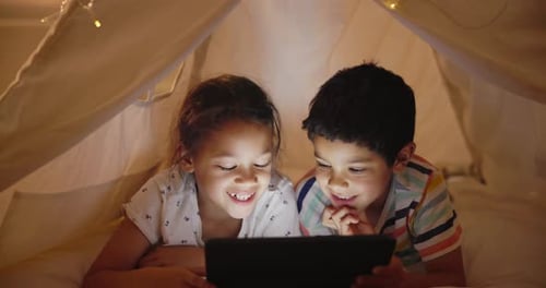Kids, tablet and online in tent at night, laughing and search social media meme for joke in bedroom