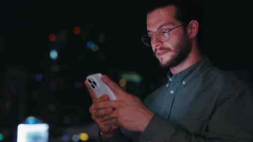 Handsome Beared Guy Chatting in Social Media While Standing Outside in the Night Street