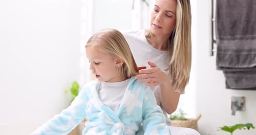 Adult Brushing Child's Hair in Bathroom