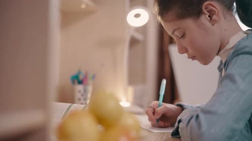 Girl Writing at a Desk Close Up