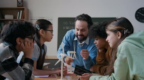 Cheerful Science Teacher Demonstrating Wind Turbine Model to Schoolchildren