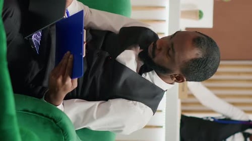 Man Reviews Notes While Sitting on a Green Chair