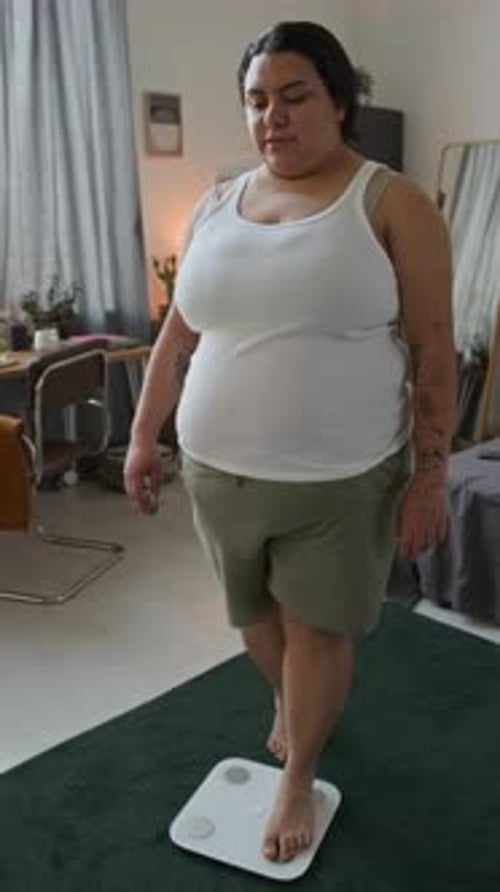 Woman Standing on Scales in Bedroom