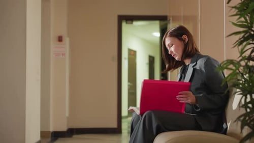 Businesswoman Reviewing Documents Alone in Office Corridor