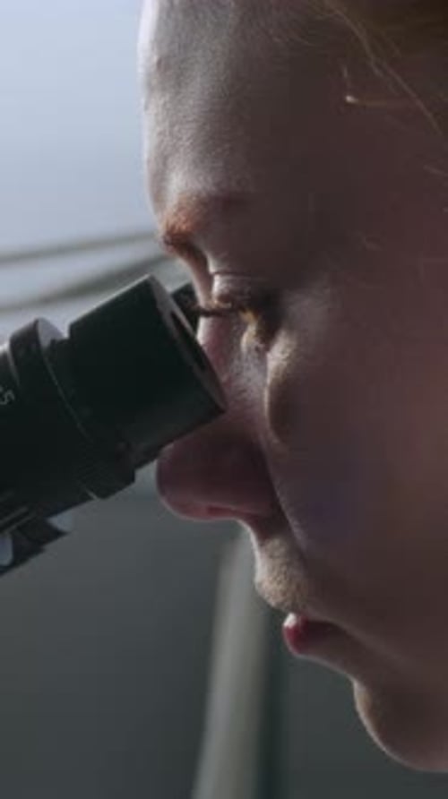 Close Up of Female Microbiologist Looking Under Microscope