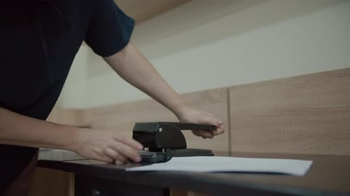 Person Using Paper Hole Puncher on Desk