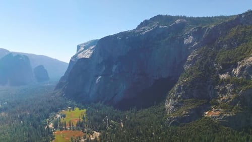 Sunlit wooded valley among the mountains of Yosemite National Park, California, USA.